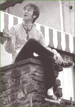 13: John Lennon, dressed in psychedelic fashion, perches upon a wall at his home in Kenwood, Weybridge, England, in 1966.